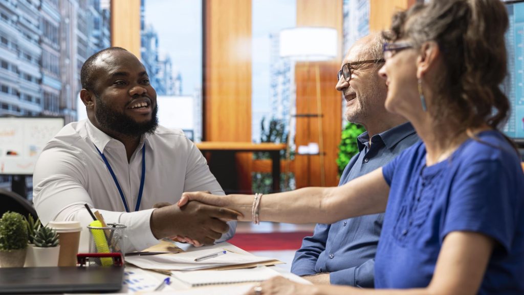 Financial advisor shaking hands with clients after approving a property purchase loan